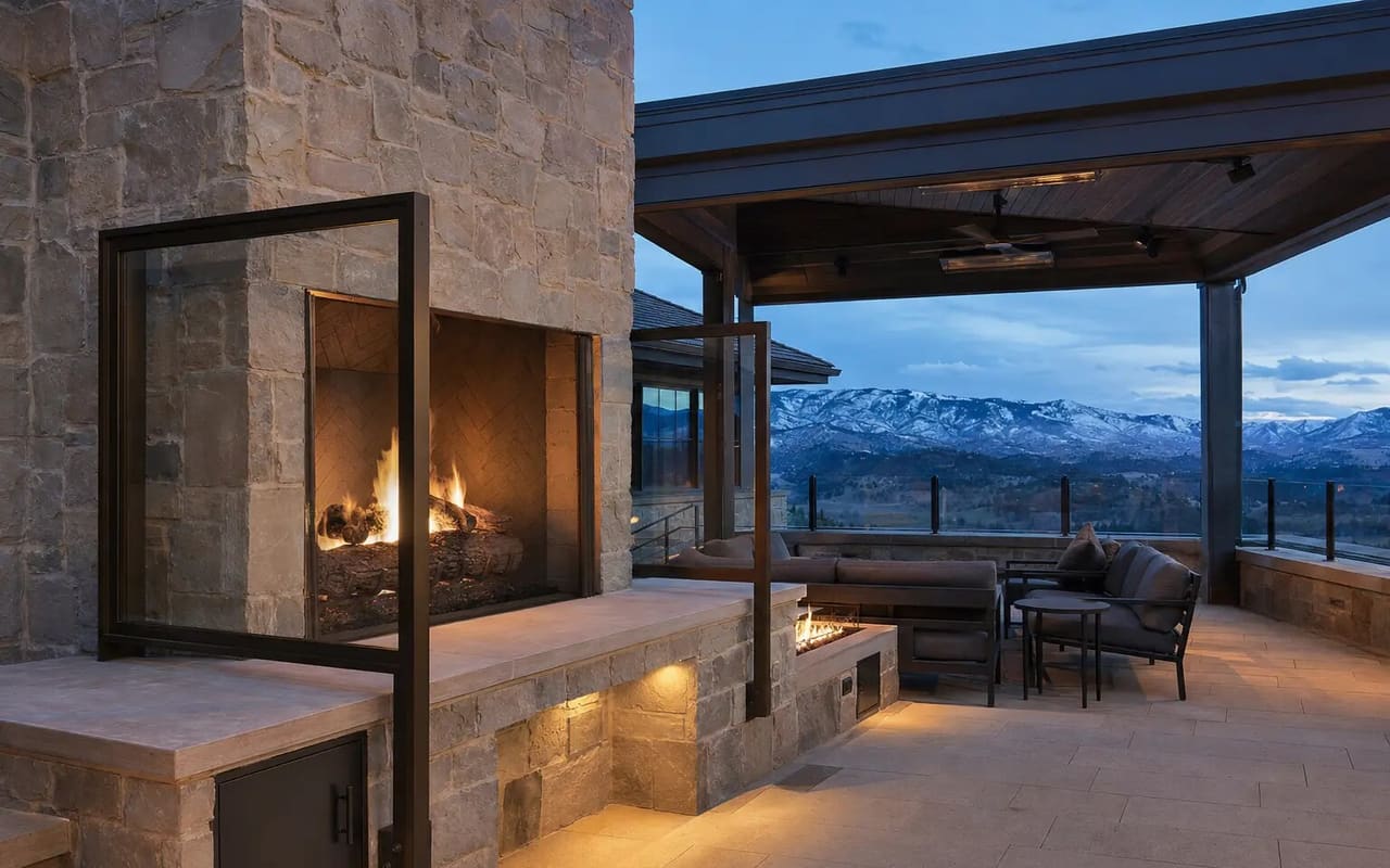 Illustrative Colorado estate with a sunken limestone lounge, linear fire wall, fire bowls, and a stone-and-glass pavilion