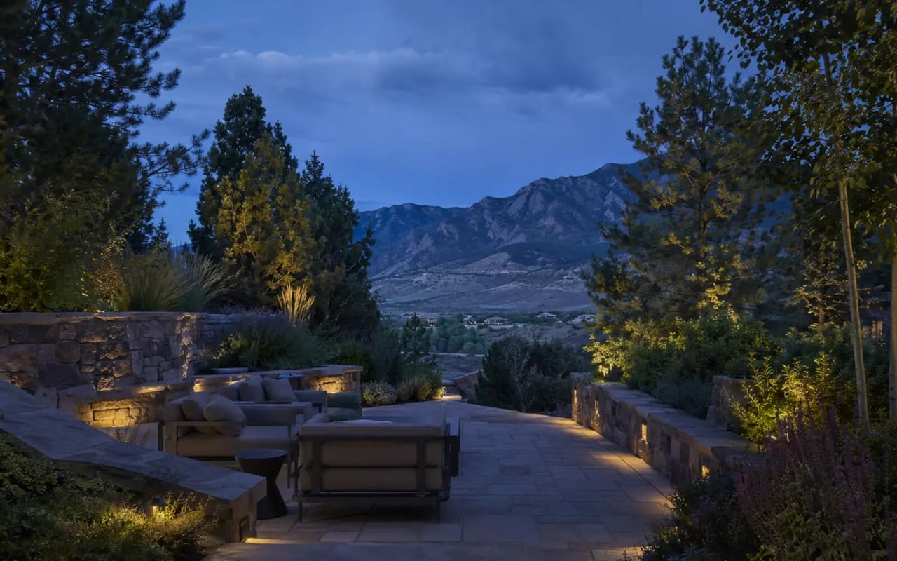 Illustrative private Colorado terrace with layered planting, sculpted stone walls, grade changes, and a mountain view